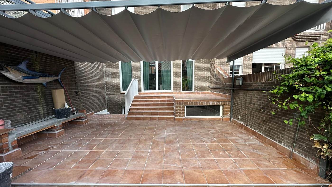 Patio reformado con solado de gres rústico, escalera y pérgola