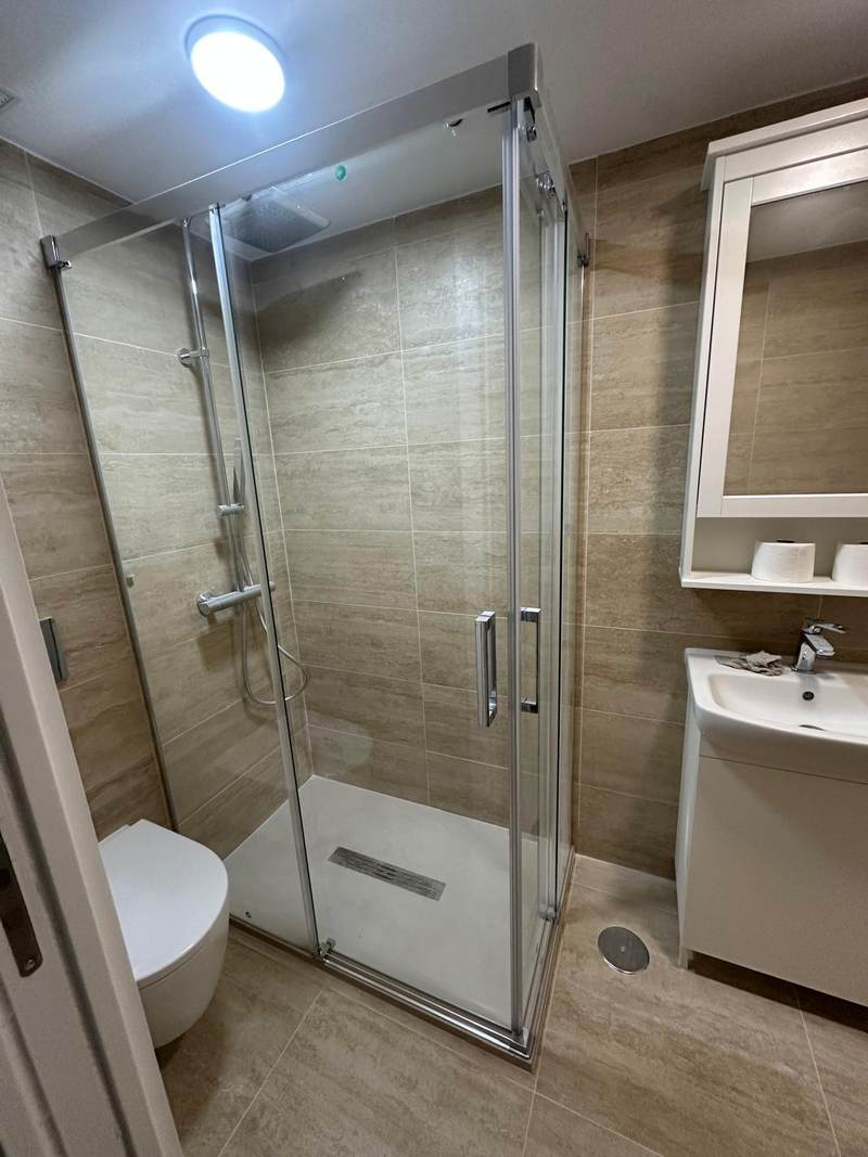 Baño terminado con alicatado de porcelánico y mampara de cristal