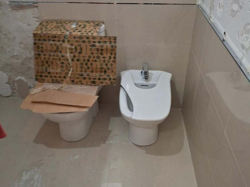Baño alicatado en tonos beige con inodoro y bidé instalados