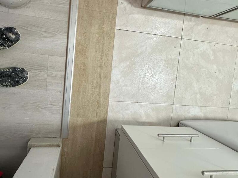 Encuentro de alicatado y mueble en baño de porcelánico travertino