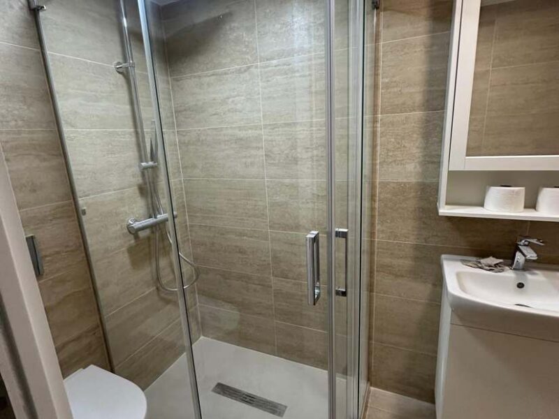 Baño completo reformado con porcelánico efecto travertino y mampara de cristal